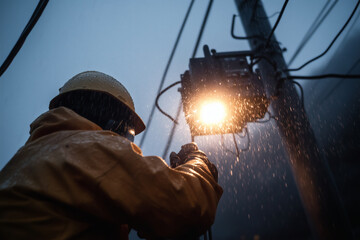 Fototapeta premium Worker repairs utility lines in stormy weather.