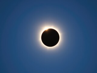 Obraz premium Solar eclipse with diamond ring effect on a clear blue sky at dawn, space beauty, diamond ring effect, natural wonder