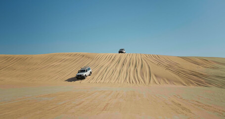Sahara desert travel destination landscape view of jeeps decend the dunes.