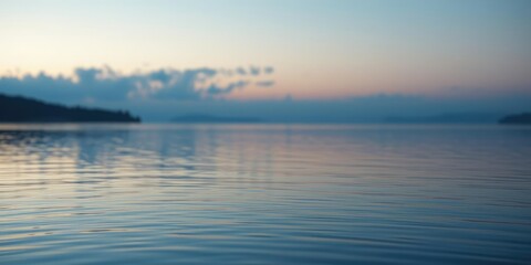 Obraz premium Soft focus on a serene lake at dawn with gentle blue hues blending into soft peach tones, natural landscape photography, soft blur effect, peaceful morning atmosphere