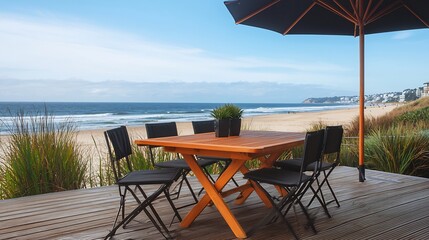 A serene beachside view featuring a wooden dining table and chairs under an umbrella