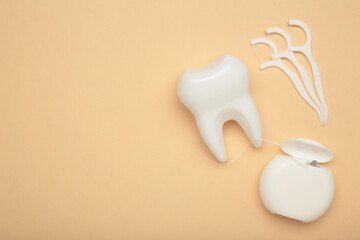 White healthy tooth with dental floss on beige. Oral dental care products, hygiene cleaning...