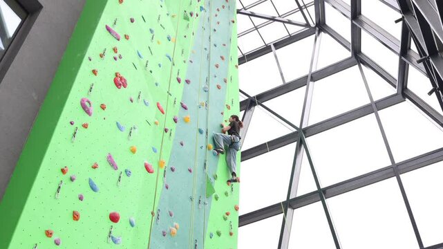 A strong girl enjoys on a climbing wall. Climbing sport, activity, fun. 