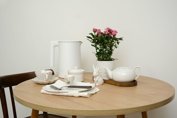 A beautifully serene dining table setting features an elegant flower pot, a lovely tea set, creating a cozy ambiance for easter.