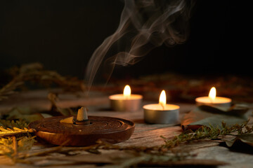 Incense burning in dim light with candles creating a tranquil atmosphere