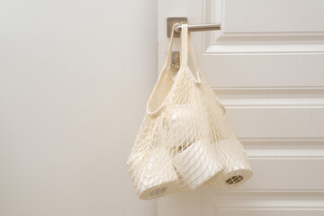 A beautifully designed and stylish grid filled with neatly arranged toilet paper rolls hangs on door handle, ideal for home organization in white background.