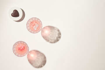Glasses of fresh pink lemonade layout with ice cubes and heart shaped dark chocolate. Spring, summer refreshing cocktails, valentines day concept, copy space