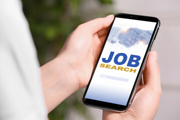 Woman looking for job using employment website on mobile phone at home, closeup