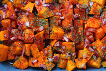 Sheet pan with pieces of butternut squash, onion, herbs and spices. Preparing pumpkin for a roast....
