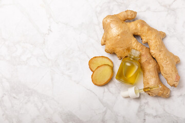 Ginger essential oil on texture background. Fresh ginger slices. Essence, serum, oil. Alternative...
