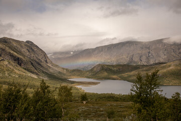 regenbogen über kleinem see mit bergen