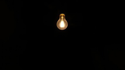 In an otherwise darkened space a lone light bulb casts its gentle warmth and light, calm, peaceful ambiance, comforting presence