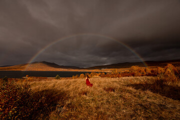 frau in rotem kleid in der ferne unter regenbogen