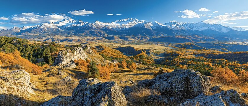 Autumnal mountain vista rocky outcrop, valley, snow-capped peaks