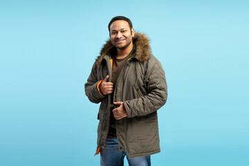 Smiling man wearing winter jacket on blue background © Maria Vitkovska