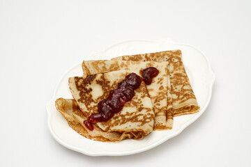 Sweet crepes assortment with berries jam on white background. Homemade food concept. Top view, flat lay