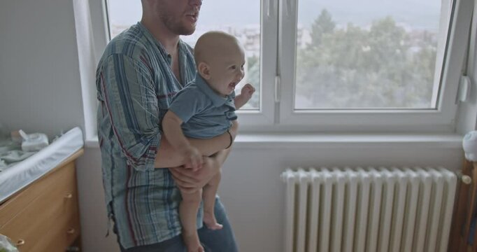 Happy parents are playing with their baby boy on the bed in his room. They are bouncing him gently and he's laughing and smiling.