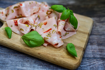 Slices Of  Traditional Italian antipasti mortadella Bolognese  on a wooden  cutting board.