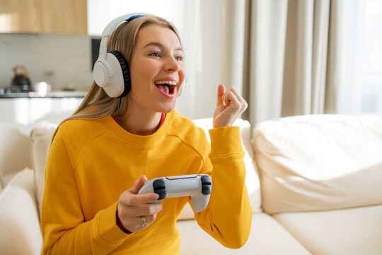Joyful woman wears headset and plays video games in a bright living room