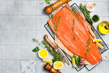 Fresh coho salmon fillet with lemon, rosemary and spices on ice. Fish cooking recipe. On a gray...