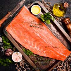 Close-up of a whole salmon or trout fillet in a metal pan, ready to cook. Top view.