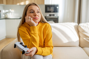 Thoughtful Woman Relaxing With Game Controller in the Living Room