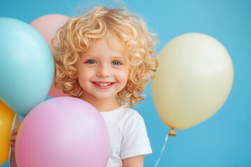 Obraz premium Portrait of cheerful toddler holding colorful balloons, celebrating a birthday or other special occasion
