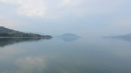 Panoramic view of a serene lake or river with calm water reflecting the surrounding natural scenery and creating a sense of tranquility, horizon, landscape, peaceful