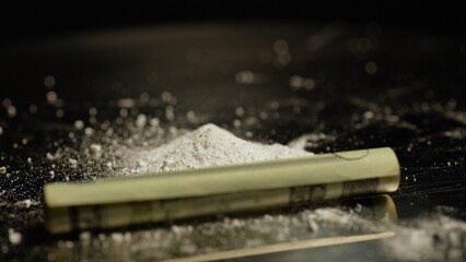 Focus on white crystalline powder made of crushed oxycodone prescription medications pills and rolled US money bill. Powdered drugs. Extreme macro close up of hand made substance and Illegal narcotic.