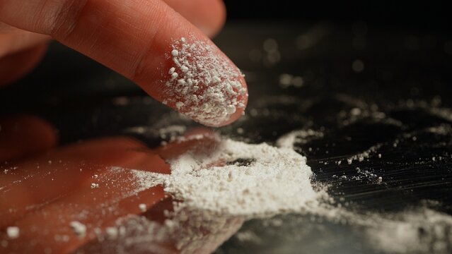 Person preparing illegal street drugs like white crystalline powder for consumption by snorting. Opioid epidemic is a major public health crisis leading to addiction, overdoses, and deaths.