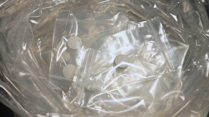 Table of drug dealer with fentanyl pills in pressed powder packed in small bag, heroin and methamphetamines, illicit drugs. Dangerous fentanyl and money bill evidence at a crime scene.