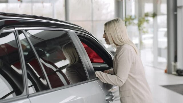 Slow motion of a woman exploring cars in a showroom with the intention to buy or test drive