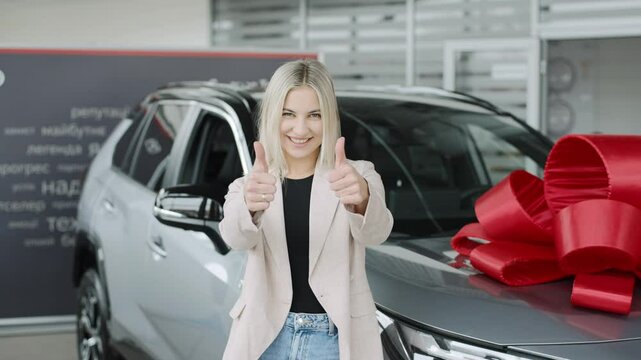Excited woman celebrating her new car purchase at a modern showroom with a festive atmosphere