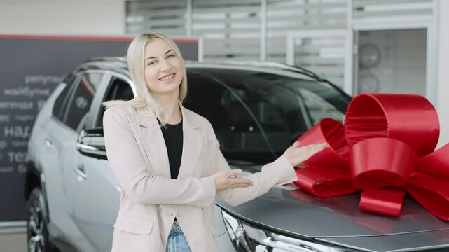 Showroom experience showcasing a woman promoting a new car with a large bow for potential buyers