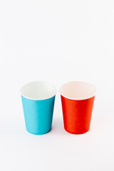 on white background two paper cups for coffee and tea painted in red and blue disposable tableware attributes for trips, recreation and picnics eco cups waterproof