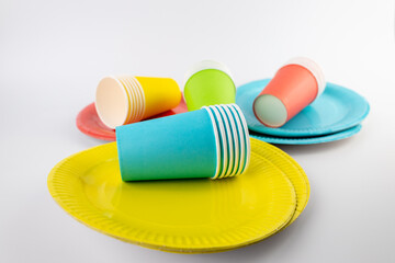 top shot on white background there are three paper cups yellow red and blue with matching paper plates set disposable tableware standard picnic set