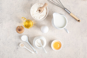 baking ingredients, egg, flour, sugar, milk and kitchen tools on a white background.
