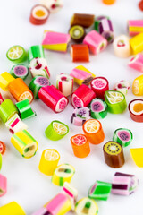 closeup on white background in a small multi-colored sugar caramels with different flavors and patterns lie children's favorite sweets a large selection risk of caries blood sugar excess weight