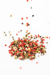 on white background a pile of mixed large aromatic peppers black red and white the main seasoning for food peppercorns indian and european spices the best variety spill from the top
