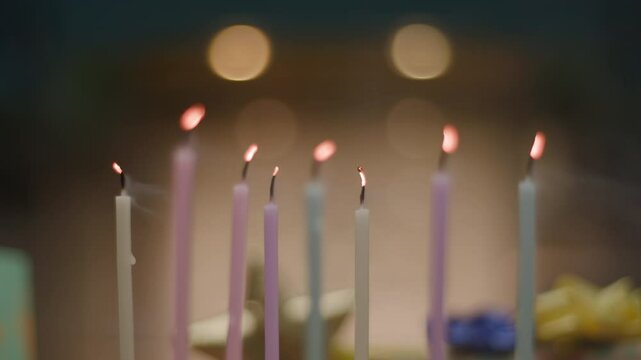 Slow-motion shot of blowing out multiple candles on a birthday cake, with flames flickering and smoke rising. Perfect for celebration, joy, and special moments themes