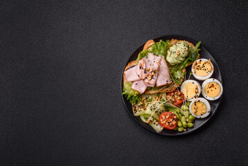 Healthy breakfast consisting of boiled eggs, slices of ham, tomatoes, green beans, aioli sauce