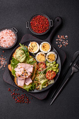 Healthy breakfast consisting of boiled eggs, slices of ham, tomatoes, green beans, aioli sauce