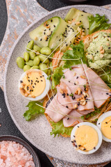 Healthy breakfast consisting of boiled eggs, slices of ham, tomatoes, green beans, aioli sauce