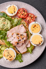 Healthy breakfast consisting of boiled eggs, slices of ham, tomatoes, green beans, aioli sauce