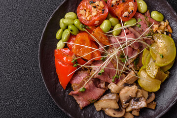 Warm salad consisting of slices of roast beef, greens, tomatoes, cucumbers, green beans