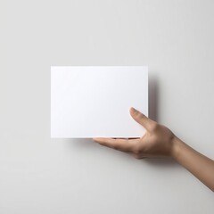 Fototapeta premium A hand holds a blank white card mockup against a minimalist background, emphasizing simplicity and potential for creativity.