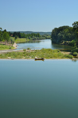 A dam on the Kupa River in Ozalj, Croatia, creates a calm pool of water reflecting the clear blue sky