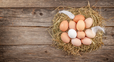 Chicken eggs in nest of straw on old wooden table background, top view. copy space © Надія Коваль