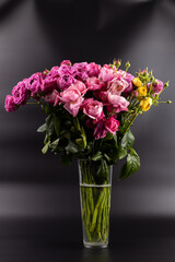 black background with iridescent light there a figured glass vase with a large bouquet of yellow and pink peony roses a gift for a beloved woman a favorite color home decoration first date March 8th