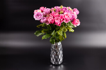 on black background with iridescent light there is a figured iron vase with a large bouquet of pink peony roses a gift for a beloved woman a favorite color home decoration first date March 8th